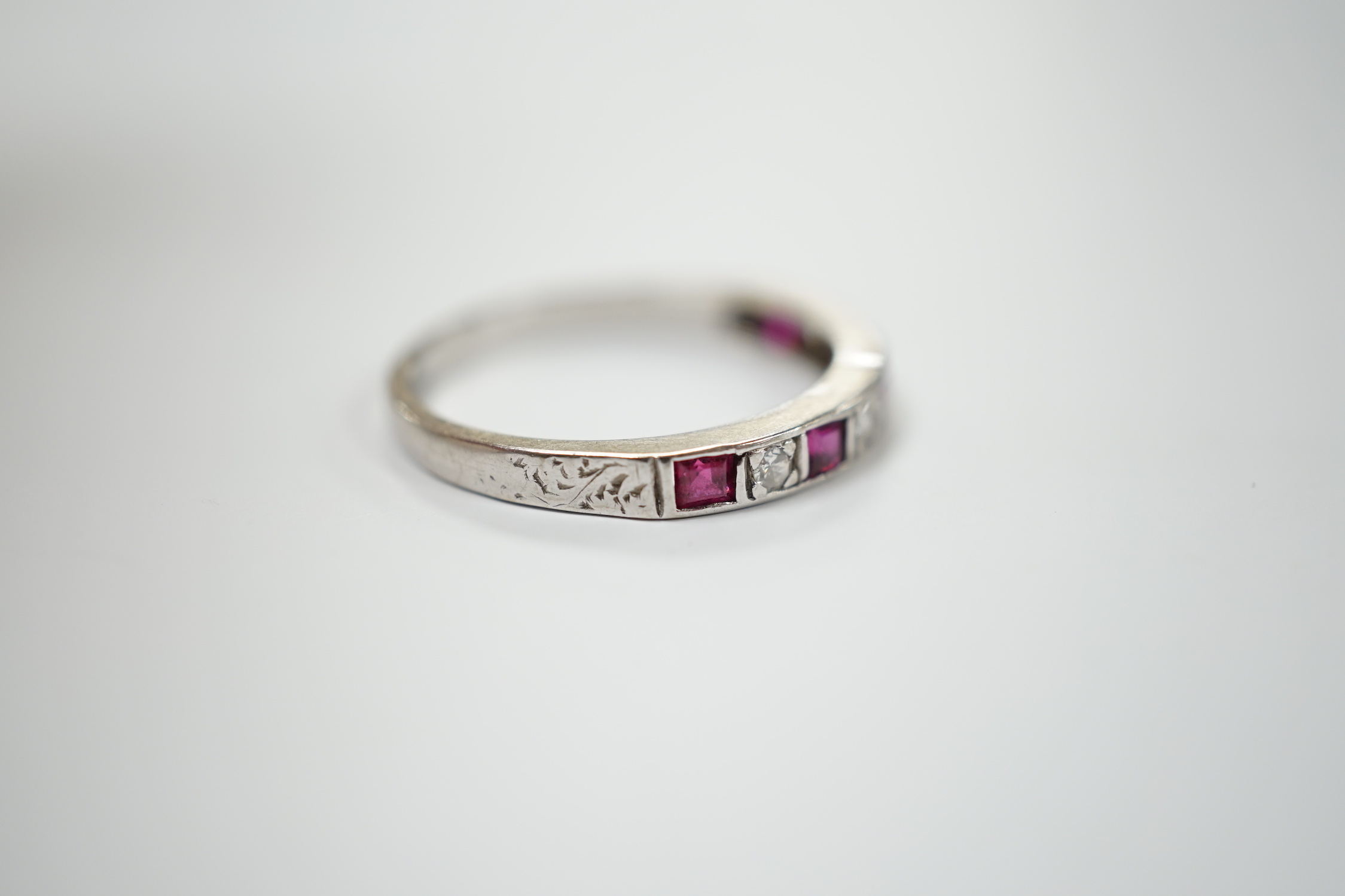 A modern 18ct white gold, ruby and diamond set half eternity ring, size O, gross weight 2.7 grams.